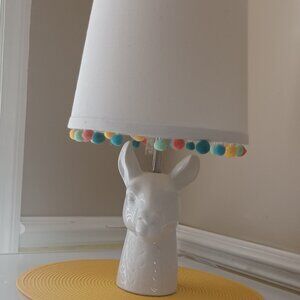 White Ceramic Llama Table Lamp With Colorful Pom-Poms Hanging From White Shade